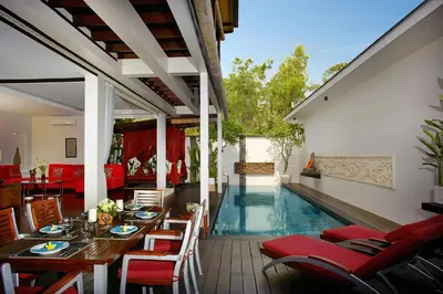 a patio with a table and chairs and a swimming pool at Temple Hill Residence Villa in Jimbaran
