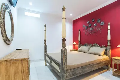 a bedroom with a bed and a red wall at Puri Agung Homestay in Kuta