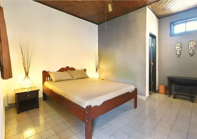a bedroom with a bed and a table and a window at Puri Agung Homestay in Kuta
