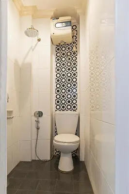 a white bathroom with a toilet and a shower at Puri Agung Homestay in Kuta