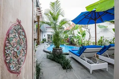 a pool with chairs and an umbrella and a mirror at Ambermoon Villa 2 in Seminyak