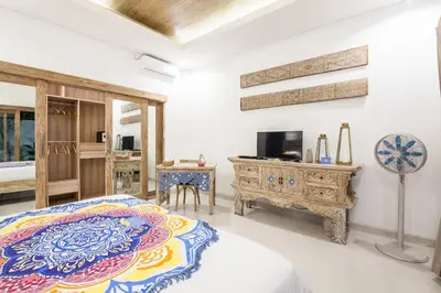 a bedroom with a bed and a tv and a table at Ambermoon Villa 2 in Seminyak