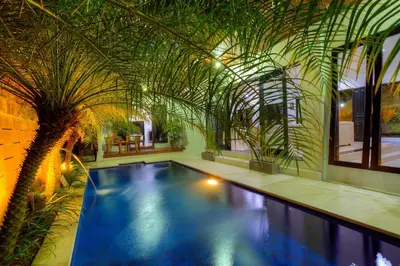 a swimming pool in a building with plants at Kedis Bali Villa in Kuta