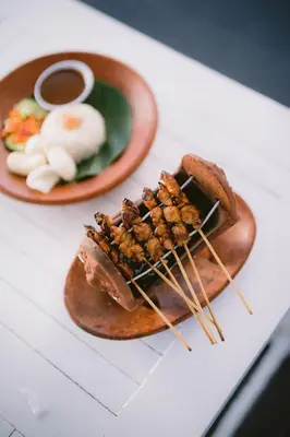 a plate of food with meat and skewers on a table at Legong Keraton Beach Hotel in Canggu
