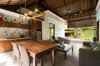 a dining room with a wooden table and chairs at Kecapi Villa Seminyak by Ini Vie Hospitality in Seminyak