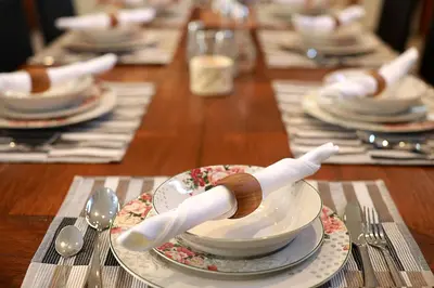 a long wooden table with plates and spoons and dishes at Villa Mawar Legian in Legian