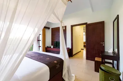 a bedroom with a canopy bed and a desk at Villa Chandraika - 3BR Private Pool Villa by AGATA in Seminyak