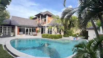 a swimming pool in front of a house at Villa Coconut Bali in Seminyak