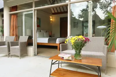 a patio with chairs and a vase of flowers on a table at Villa Coconut Bali in Seminyak