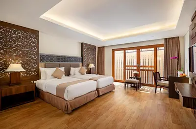 a hotel room with a large bed and a desk at Villa Kayu Raja in Seminyak