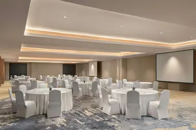 a conference room with white tables and chairs and a screen at Fairfield by Marriott Bali Kuta Ngurah Rai in Kuta