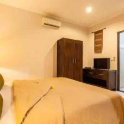 a bedroom with a bed and a dresser in it at Surya Mas Villa in Legian