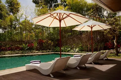 a row of chairs and umbrellas next to a pool at Del Cielo Villa Jimbaran in Jimbaran