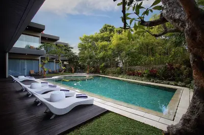 a swimming pool with lounge chairs next to a house at Del Cielo Villa Jimbaran in Jimbaran