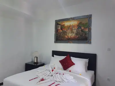 a bedroom with a bed with a painting on the wall at Palm Bamboo Hotel in Nusa Dua