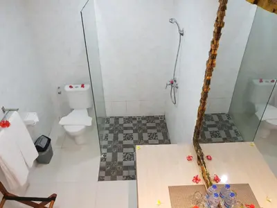 a bathroom with a toilet and a glass shower at Palm Bamboo Hotel in Nusa Dua