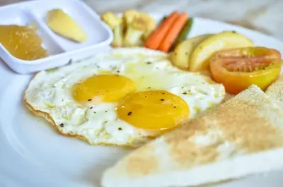 a plate with two eggs and bread and vegetables at Palm Bamboo Hotel in Nusa Dua