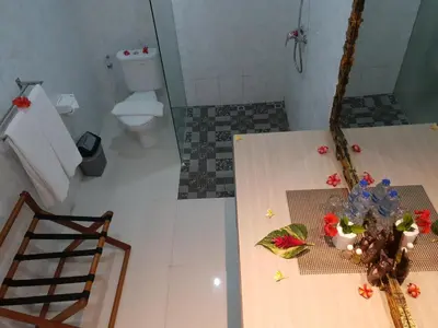 a bathroom with a toilet and a table with flowers on it at Palm Bamboo Hotel in Nusa Dua
