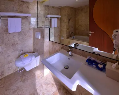 a bathroom with a sink and a toilet and a tub at Serela Kuta in Kuta