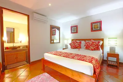 a bedroom with a large bed and a bathroom at Villa Santi Seminyak in Seminyak