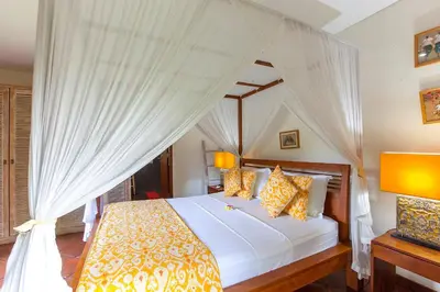 a bedroom with a canopy bed with yellow pillows at Villa Santi Seminyak in Seminyak