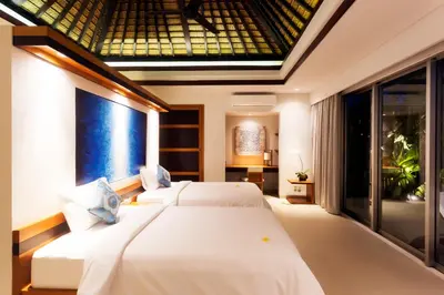 a bedroom with two beds and a large window at Villa by the Beach in Jimbaran