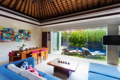 a living room with a blue couch and a table at Villa by the Beach in Jimbaran