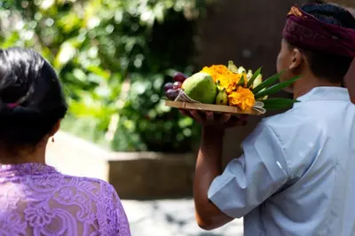 a woman is holding a plate of fruit and flowers at Adepa Resort in Canggu