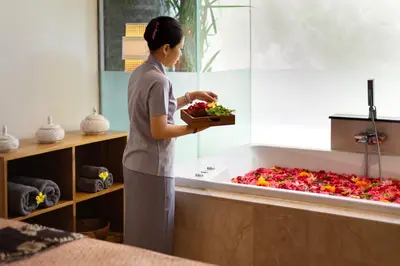 a woman standing in a bath tub with a tray of flowers at Adepa Resort in Canggu