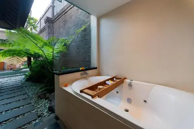 a bath tub in a bathroom with a plant at Adepa Resort in Canggu