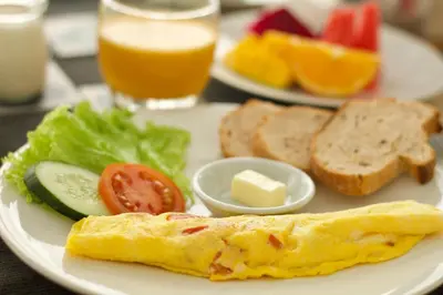 a white plate with an omelet and bread and vegetables and toast at Villa Alina in Seminyak