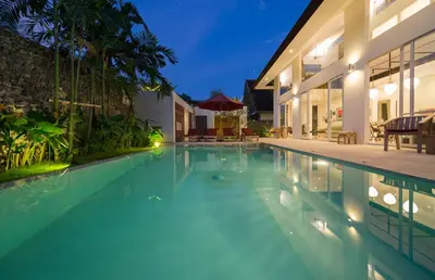 a swimming pool in front of a house at night at Villa Alina in Seminyak