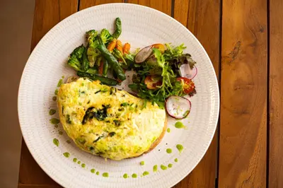 a white plate with a chicken and vegetables on a table at The Daha Luxury Villas in Seminyak