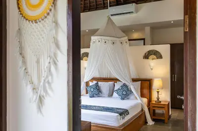 a bedroom with a bed with a canopy at Villa Tiga Mangga by Optimum Bali Villas in Seminyak