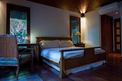 a bedroom with a bed and a chair and windows at D'Sriwing Villa Gallery in Kuta