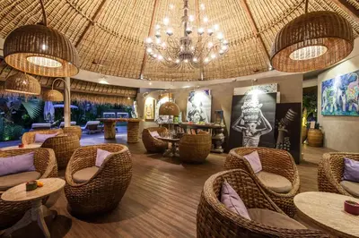 a restaurant with wicker chairs and tables and a chandelier at Blue Karma Dijiwa Seminyak in Seminyak