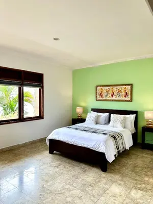 a bedroom with a large bed with green walls at Ellies Hotel in Nusa Dua