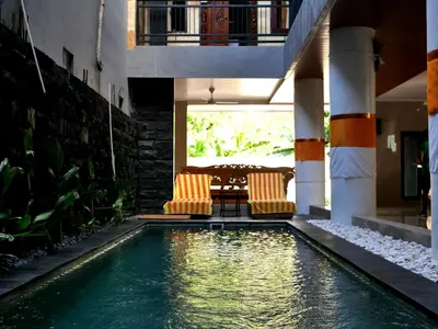 a pool with two chairs and a table in a house at Vivaldi Jimbaran in Jimbaran