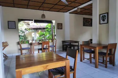 a dining room with wooden tables and chairs at Villa Puri Royan Jimbaran in Jimbaran