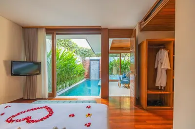 a bedroom with a bed and a tv and a pool at Maca Villas and Residence Umalas in Seminyak