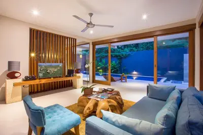a living room with a blue couch and a table at Maca Villas and Residence Umalas in Seminyak