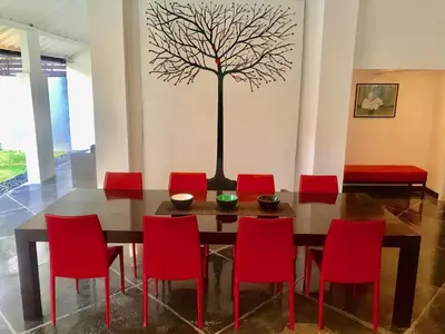 a dining room table with red chairs and a tree on the wall at Villa JULIA | heart of Seminyak | 350m Beach in Seminyak