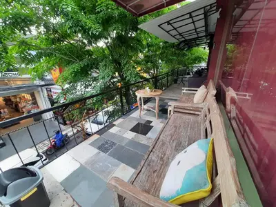 a balcony with a bench and a table and trees at The Legian 777 in Legian