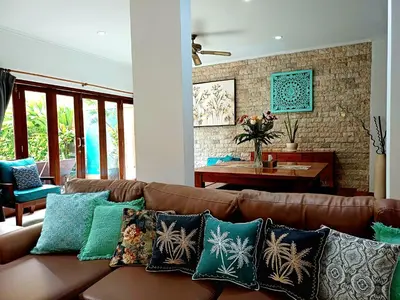 a living room with a brown couch with pillows at Villa Kora in Seminyak