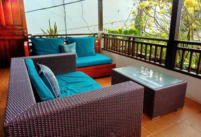 a balcony with two wicker chairs and a table at Villa Kora in Seminyak