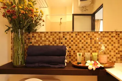 a bathroom shelf with a vase of flowers and towels at Sanur Seaview Hotel in Sanur