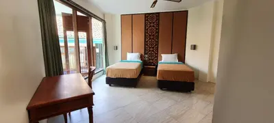 a room with two beds and a desk and a window at Sanur Seaview Hotel in Sanur