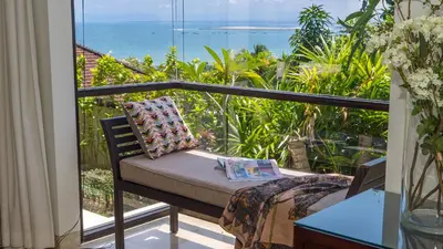 a balcony with a couch and a view of the ocean at Villa Adenium by Elite Havens in Jimbaran