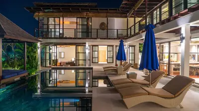 a villa with a swimming pool with chairs and umbrellas at Villa Adenium by Elite Havens in Jimbaran