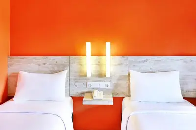 two beds in a room with an orange wall at Primera Hotel Seminyak in Seminyak